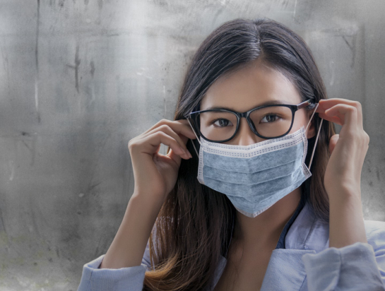 Woman wearing face mask and clear glasses lenses thanks to Optifog lens coating