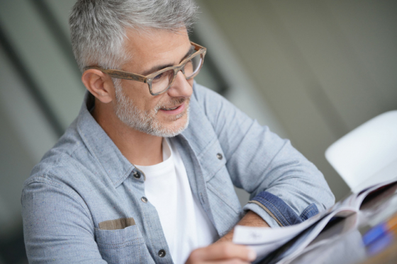 Man wearing varifocal lenses smiling when reading his newspaper