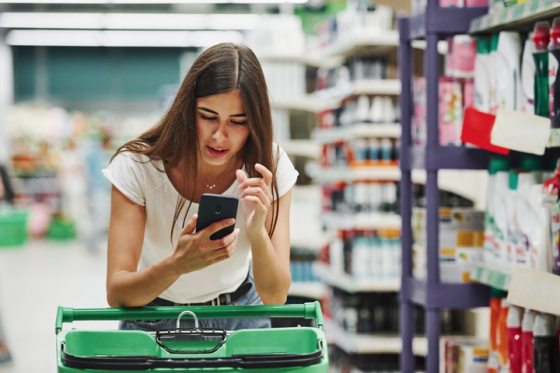 Woman in supermarket struggling to read her phone screen due to issues with teaming